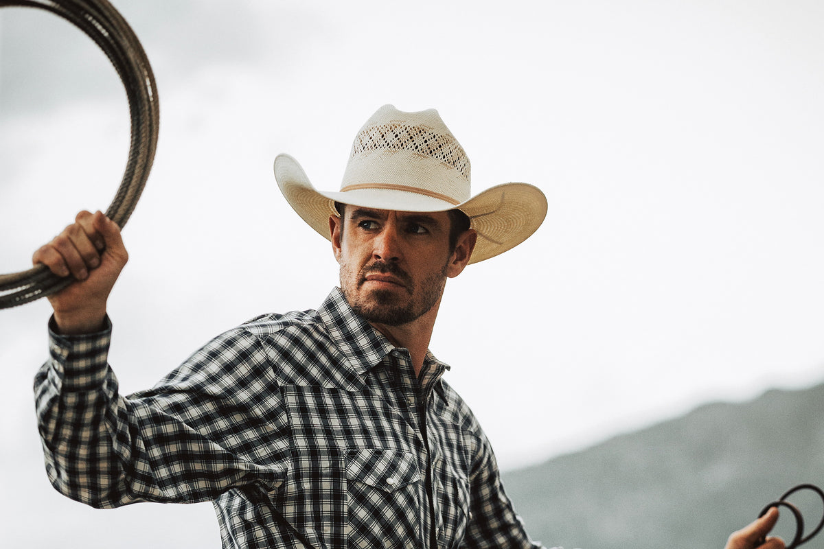 A straw cowboy hat with a cattleman crease and a classic side-curl brim