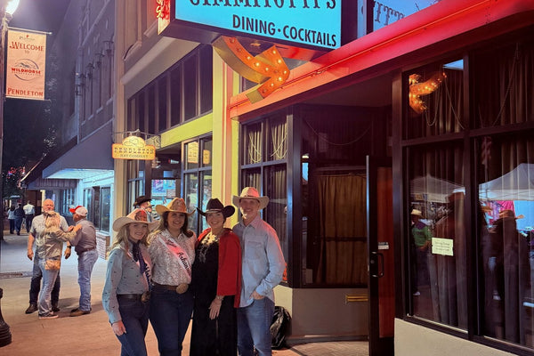 Zack and Natalie with two rodeo queens outside the neon storefront of Virgil's at Cimmiyotti's during Pendleton Round-Up week
