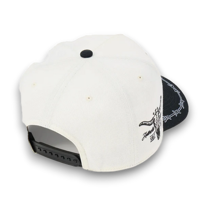 Rafter M Hat Company cream trucker hat with black brim, barbed wire detail, and bull skull embroidery. Adjustable snapback.